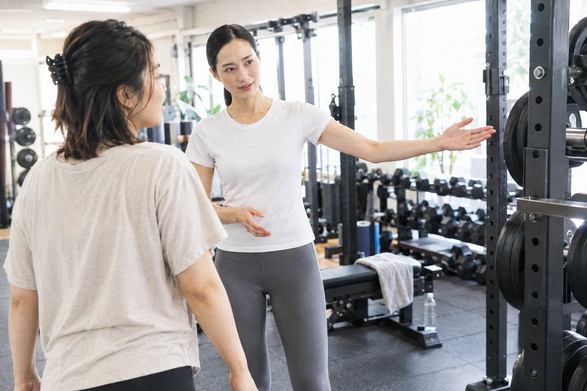 ラックを指して設備を案内するトレーナーと利用者