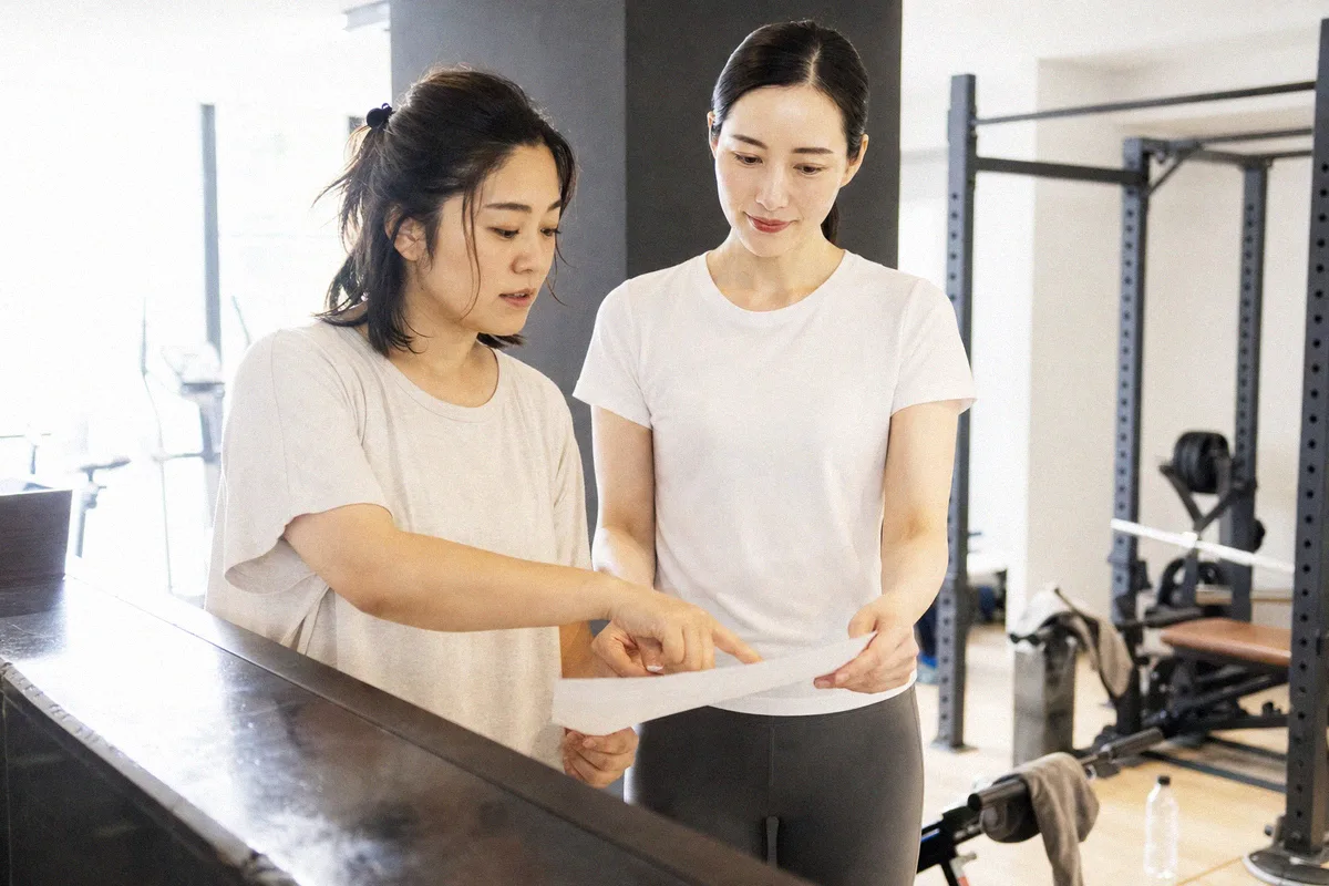 カウンセリングでメニューの内容を確認する利用者とトレーナー