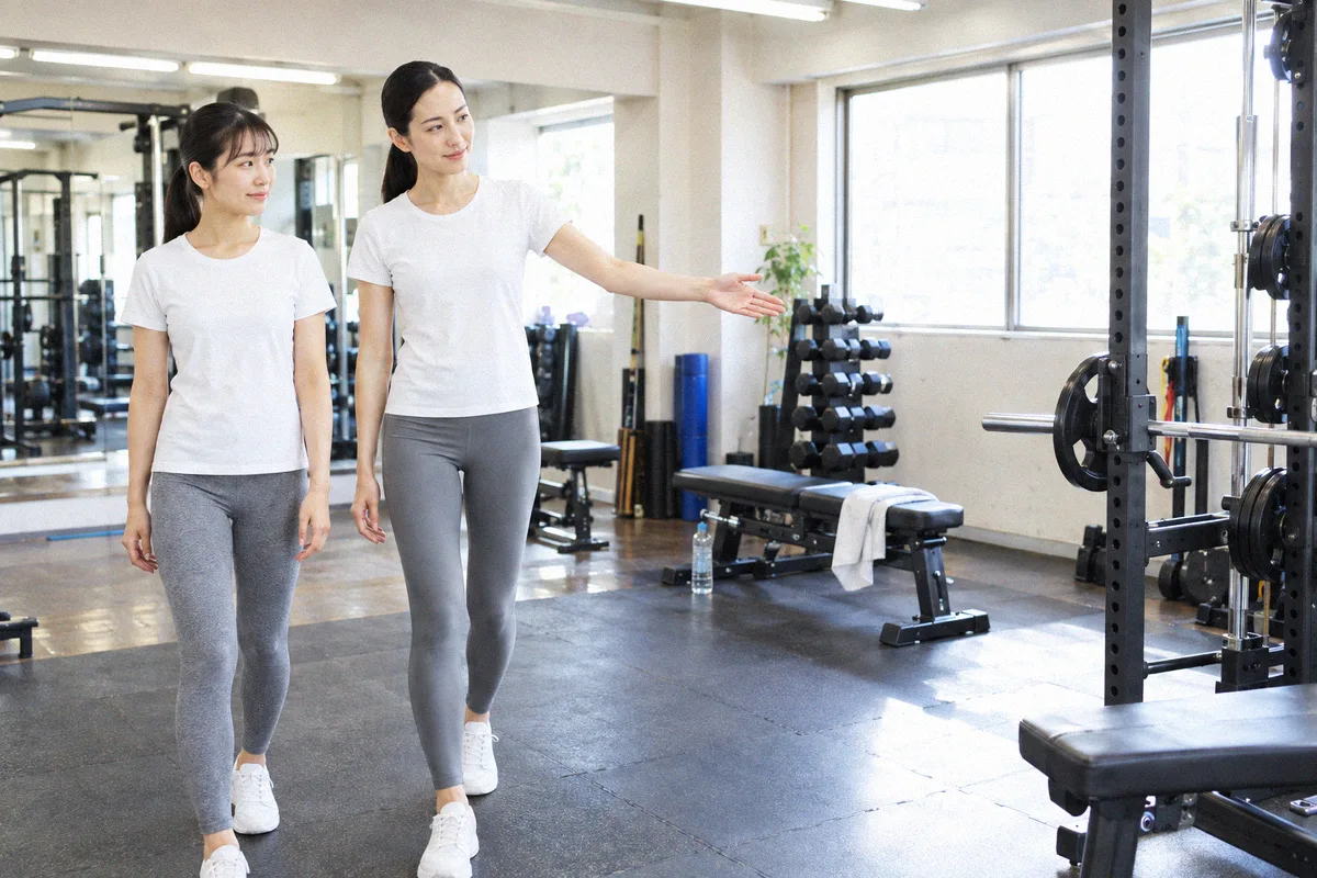 ラックを指して設備を案内するトレーナーと利用者