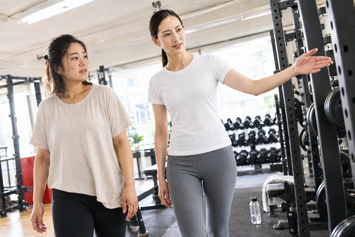 ラックを指して設備を案内するトレーナーと利用者