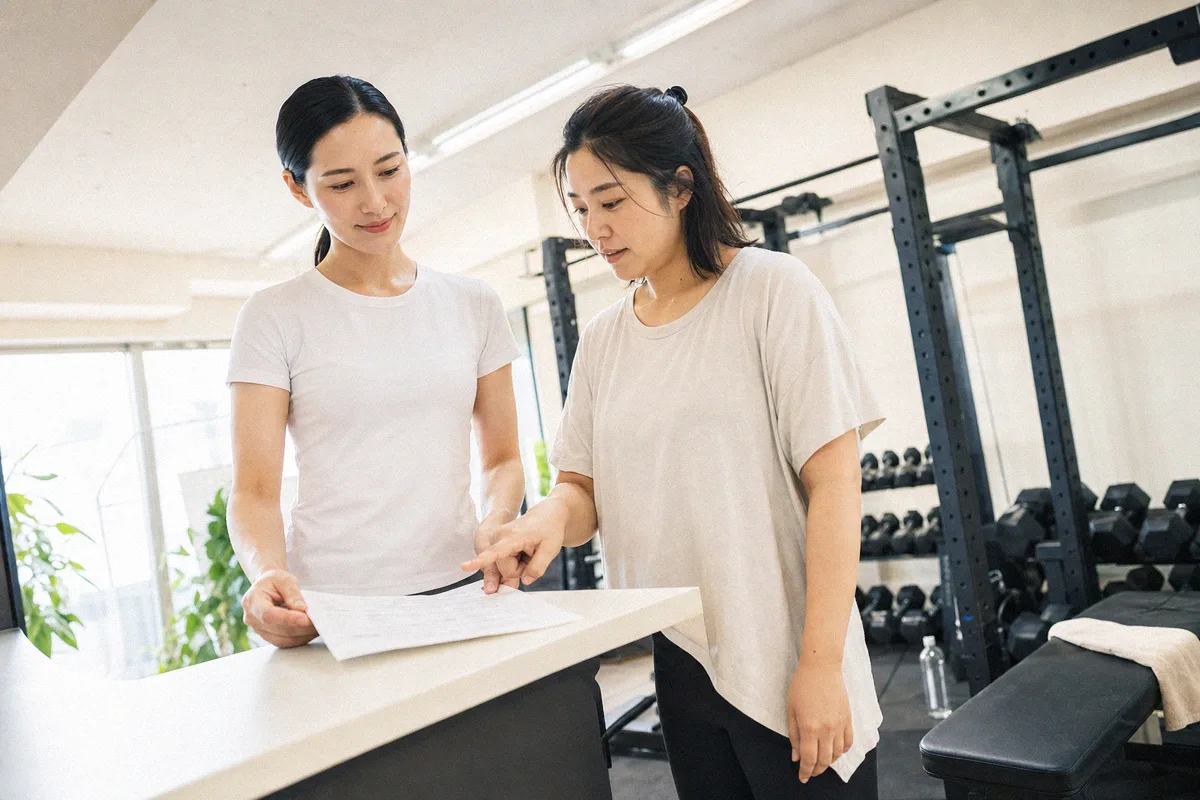 テーブル越しに料金や進め方について話すトレーナーと利用者