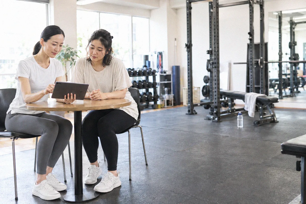 タブレットを見ながらトレーニング計画の説明を受ける利用者とトレーナー