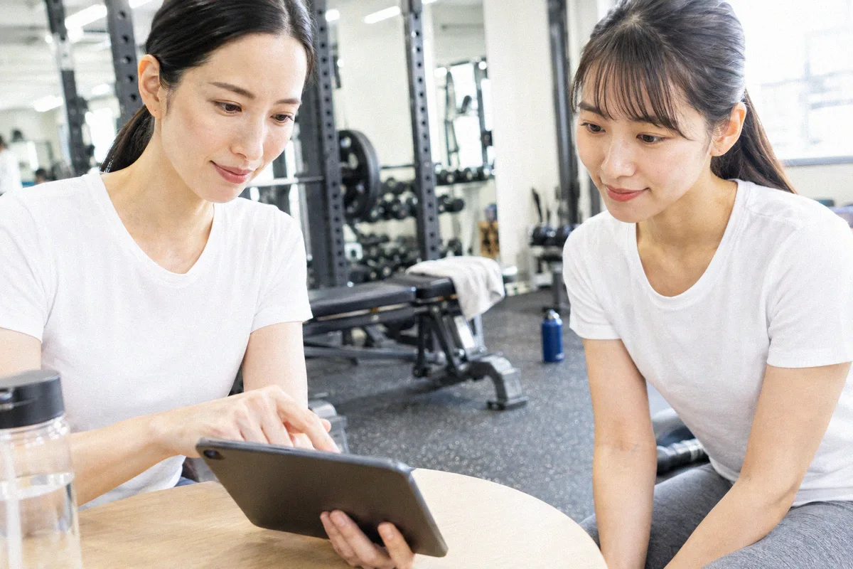 タブレットを見ながらトレーニング計画の説明を受ける利用者とトレーナー
