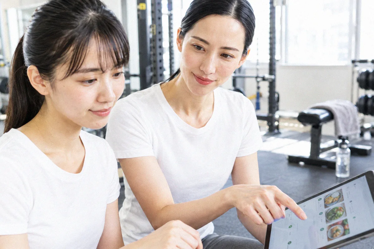 食事記録アプリの画面を一緒に確認する利用者とトレーナー