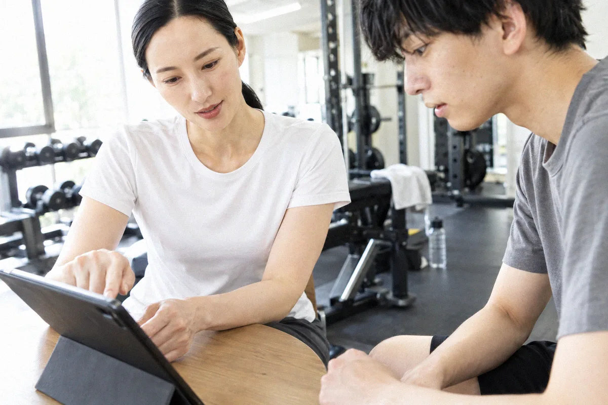 タブレットを見ながらトレーニング計画の説明を受ける利用者とトレーナー