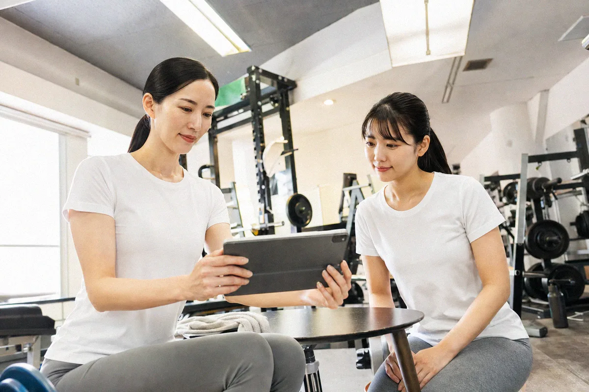 テーブル越しに料金や進め方について話すトレーナーと利用者