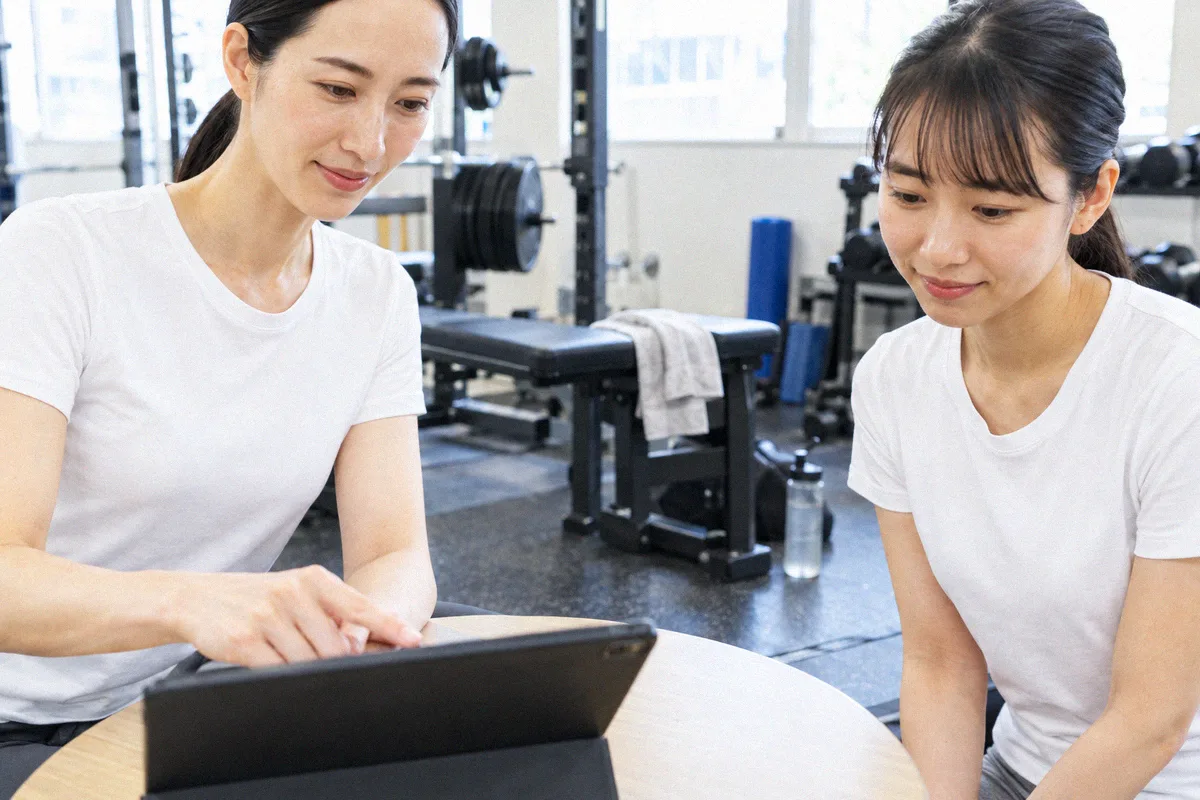 タブレットを見ながらトレーニング計画の説明を受ける利用者とトレーナー