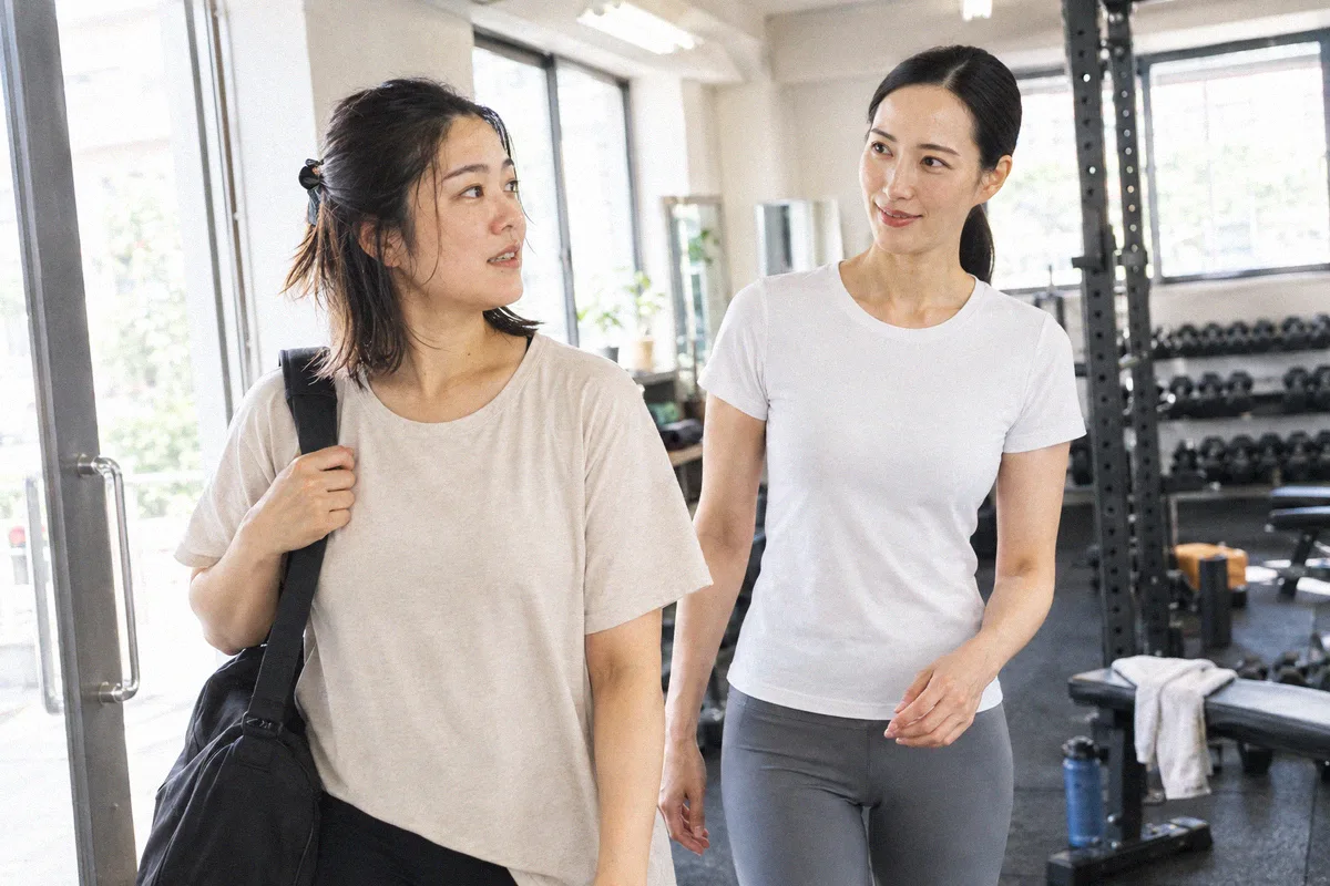 トレーニングバッグを持って来店した利用者を迎えるトレーナー