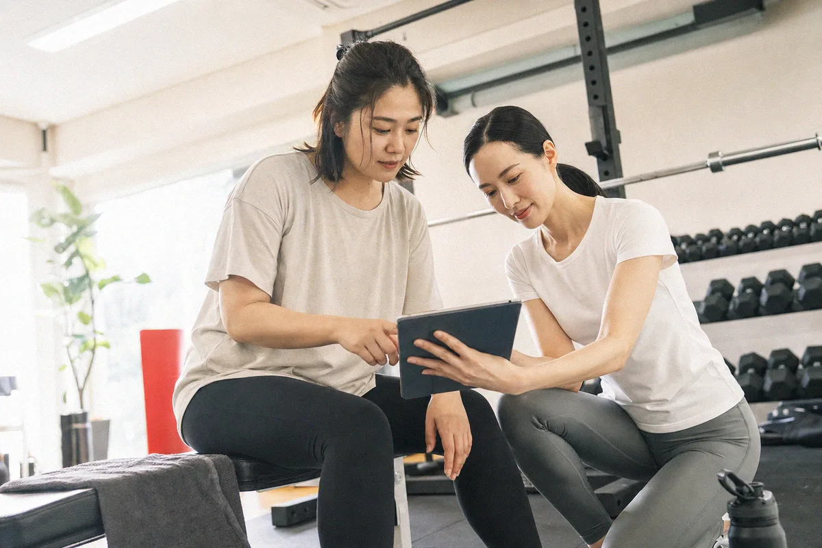テーブル越しに料金や進め方について話すトレーナーと利用者