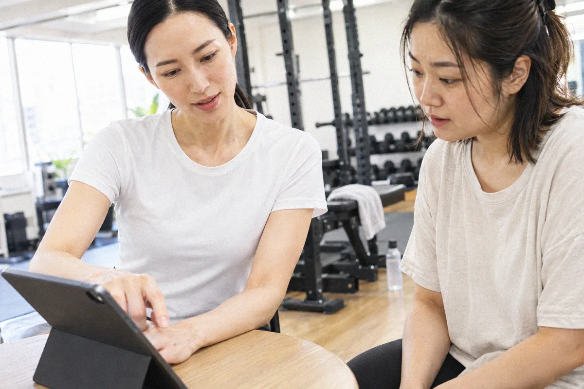 タブレットを見ながらトレーニング計画の説明を受ける利用者とトレーナー