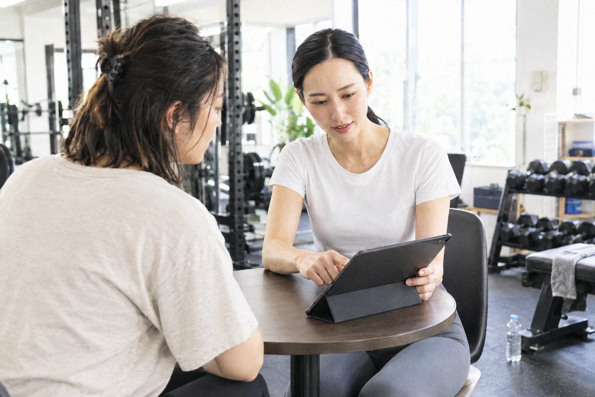 タブレットを見ながらトレーニング計画の説明を受ける利用者とトレーナー
